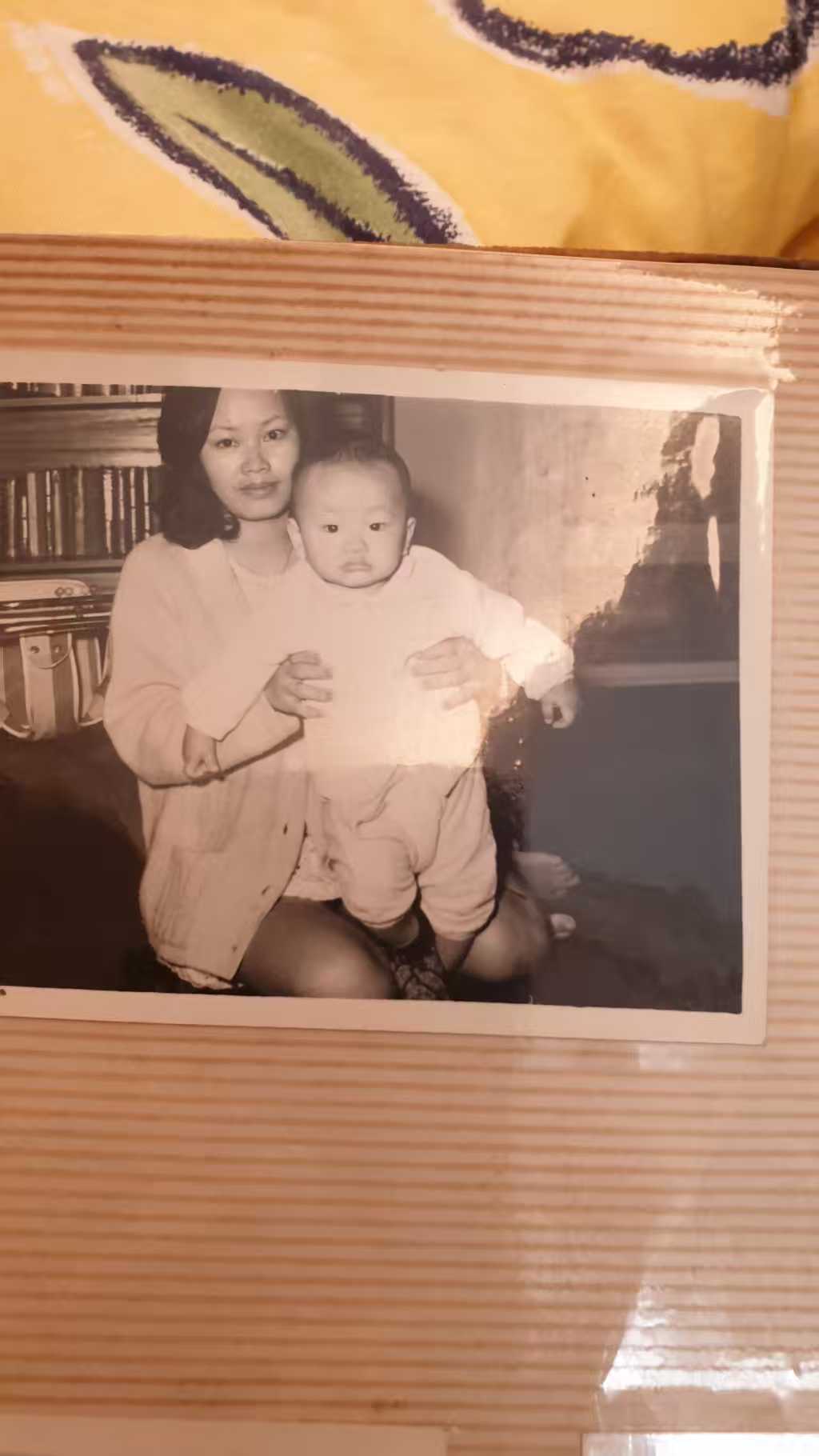 手机拍摄的纸质旧照片原图，周围仍有桌面、床单、白边和反光